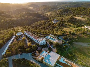 An aerial view of a resort with multiple buildings, a swimming pool, and a winding road.