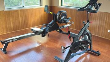 An indoor gym with an air rower and a stationary bike.
