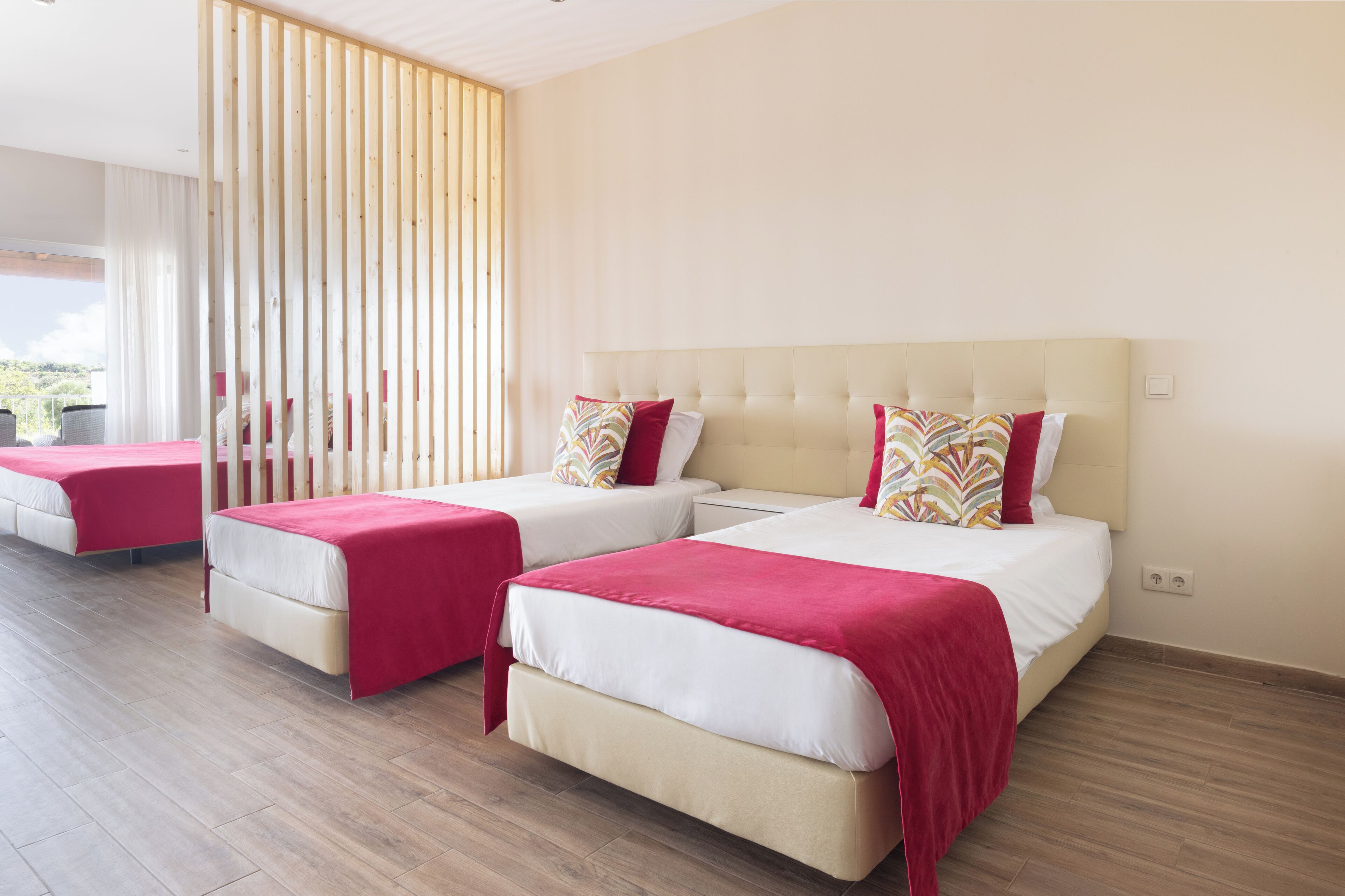 A hotel room with two beds, a balcony, and a view of the outdoors.