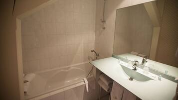 Une salle de bain avec une baignoire, un lavabo et un miroir.