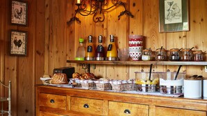 Interior de madera con un bufé de desayuno, que incluye pan, bollería y salsas.