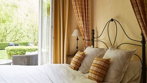 Un dormitorio con cama, almohadas, mesita de noche, lámpara y ventana con cortinas.
