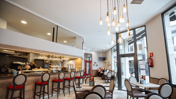 A modern restaurant with a bar area, seating, and large windows. - Hotel Don Manuel (Gijon)