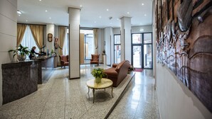 A hotel lobby with a reception desk, seating area, and a decorative wall. - Hotel Don Manuel (Gijon)