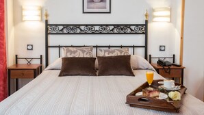 A neatly made bed with a tray of breakfast including juice, coffee, and cake, and a phone on a bedside table. - Hotel Don Manuel (Gijon)