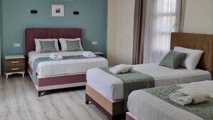 Habitación de hotel con dos camas, ventilador de techo, aire acondicionado y ventana con cortinas.