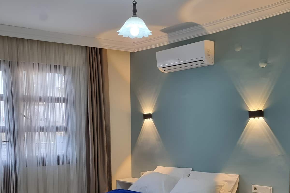 Een slaapkamer met een bed, twee nachtkastjes, een airconditioning en een plafondlamp.
