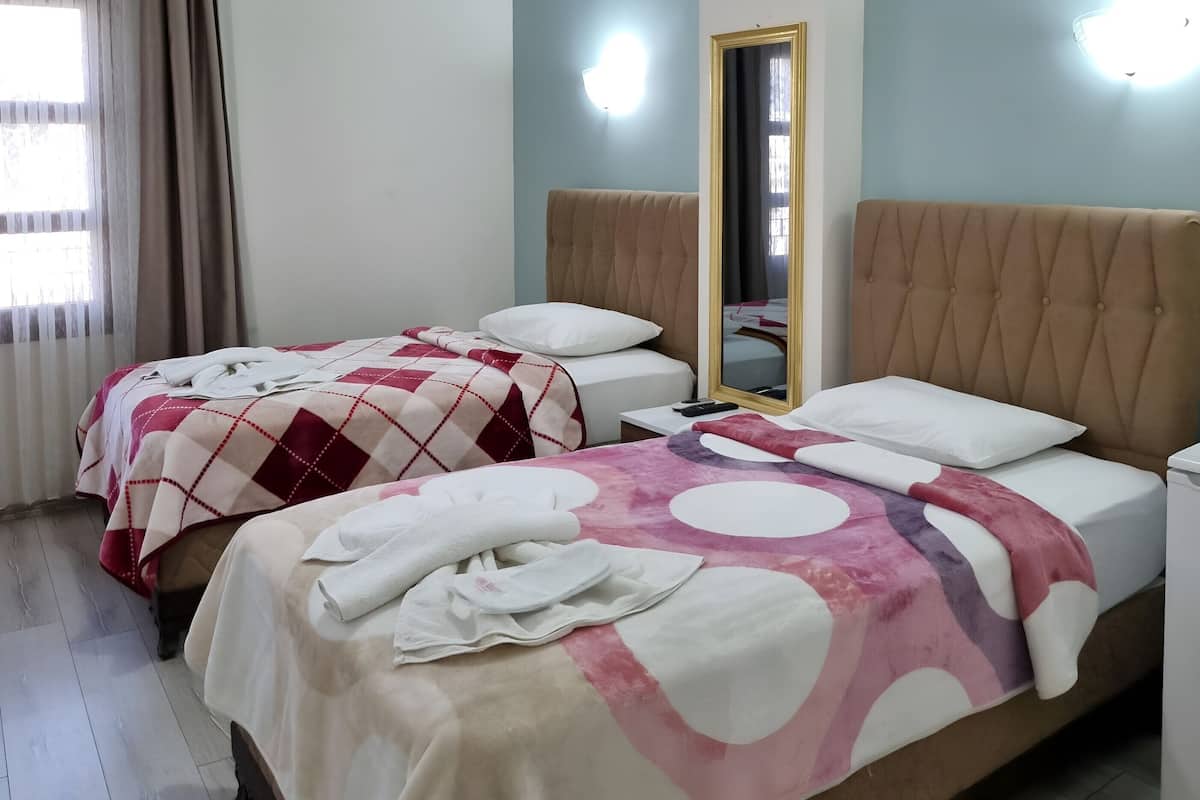 Een hotelkamer met twee bedden, een spiegel en een lamp.