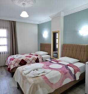 Ein Hotelzimmer mit zwei Betten, einem Spiegel und einer Lampe.