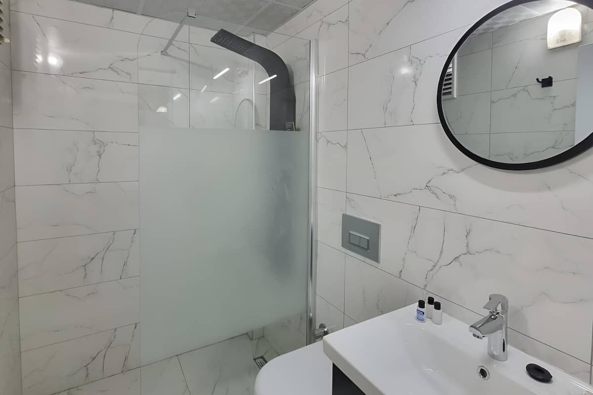 Een moderne badkamer met een douchecabine van glas, een wit toilet en een wastafel met spiegel erboven.