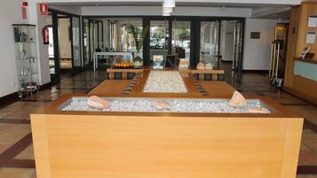 Relax in the welcoming lobby, featuring a central seating area, water feature, and glass door leading to an outdoor view.