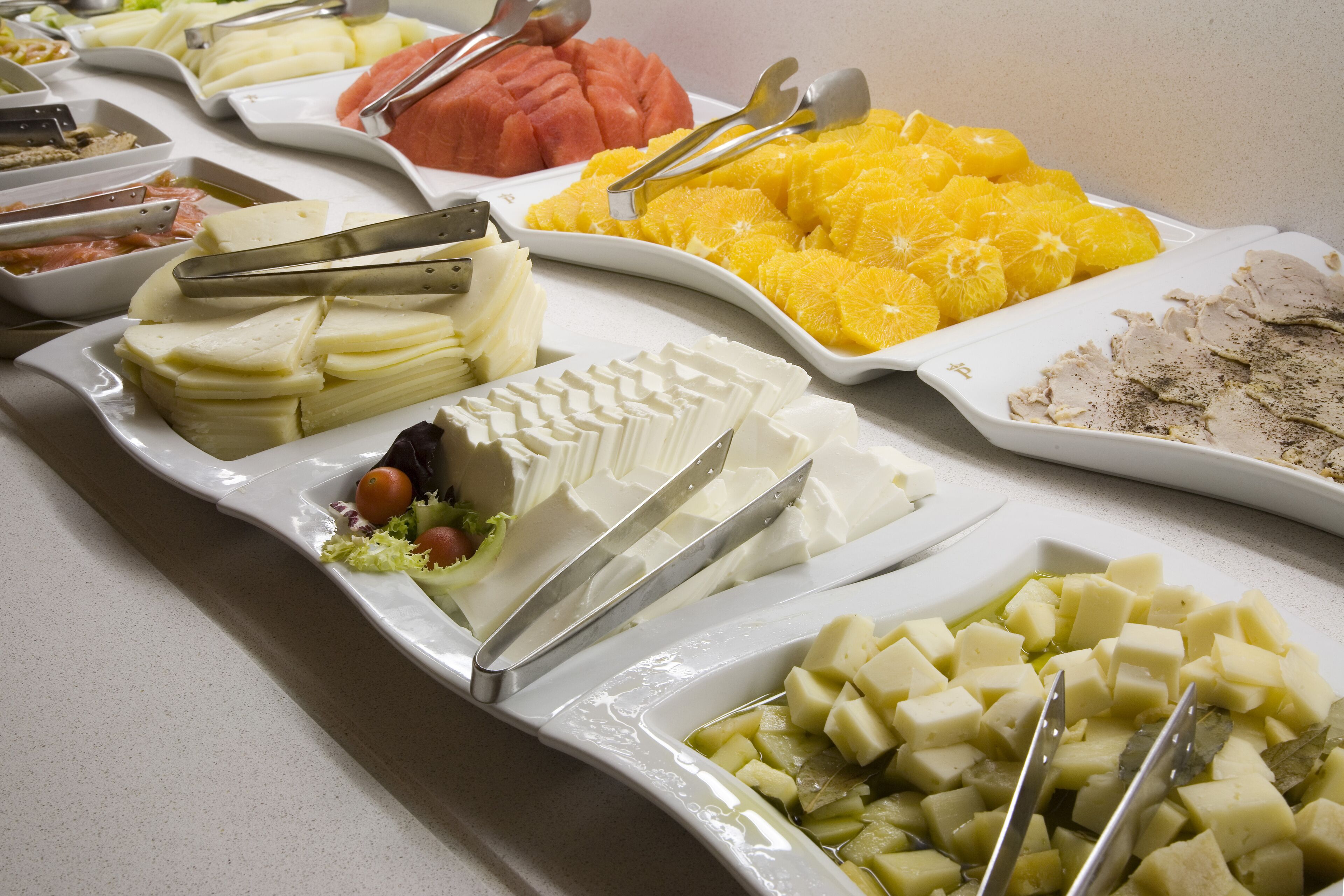 A buffet with various food items including cheese, fruits, and vegetables.