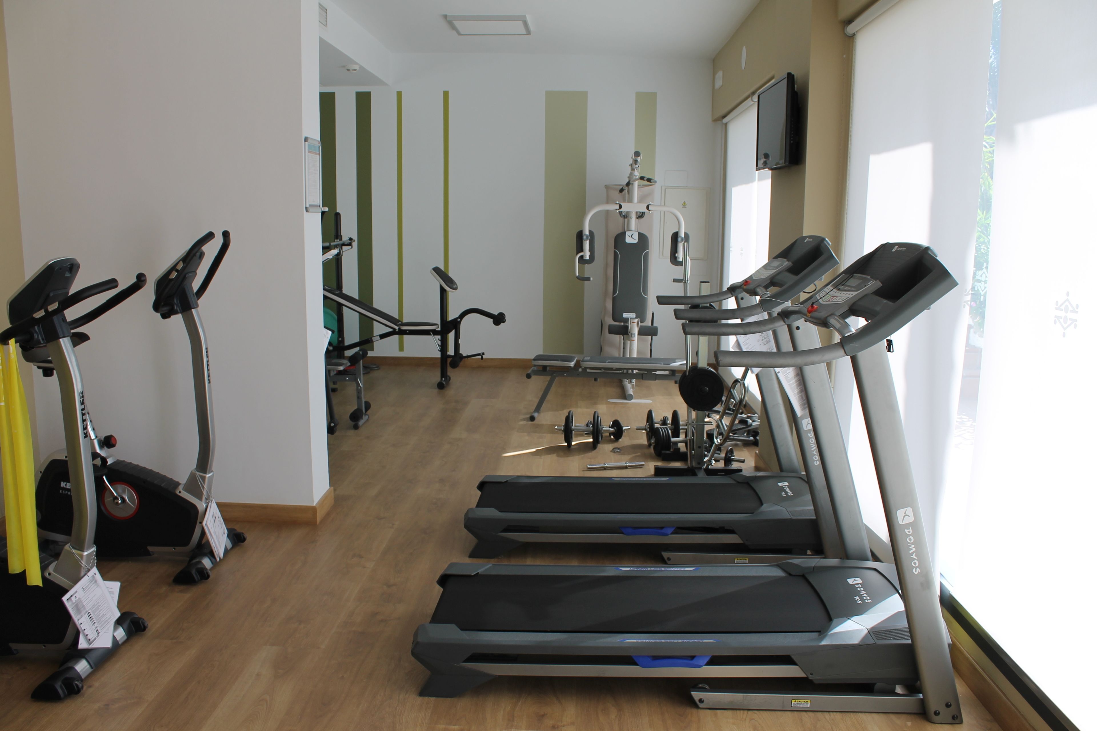 Un gimnasio con cintas de correr, bicicletas estáticas y máquinas de pesas.