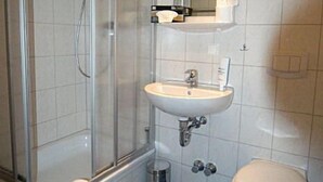 A bathroom with a glass shower enclosure, a sink, a toilet, and a mirror.