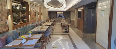 Un restaurante con una barra larga, asientos acolchados y un techo decorativo.