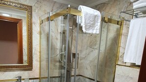 Un baño con suelo de mármol, ducha con cerramiento de vidrio, lavabo e inodoro.