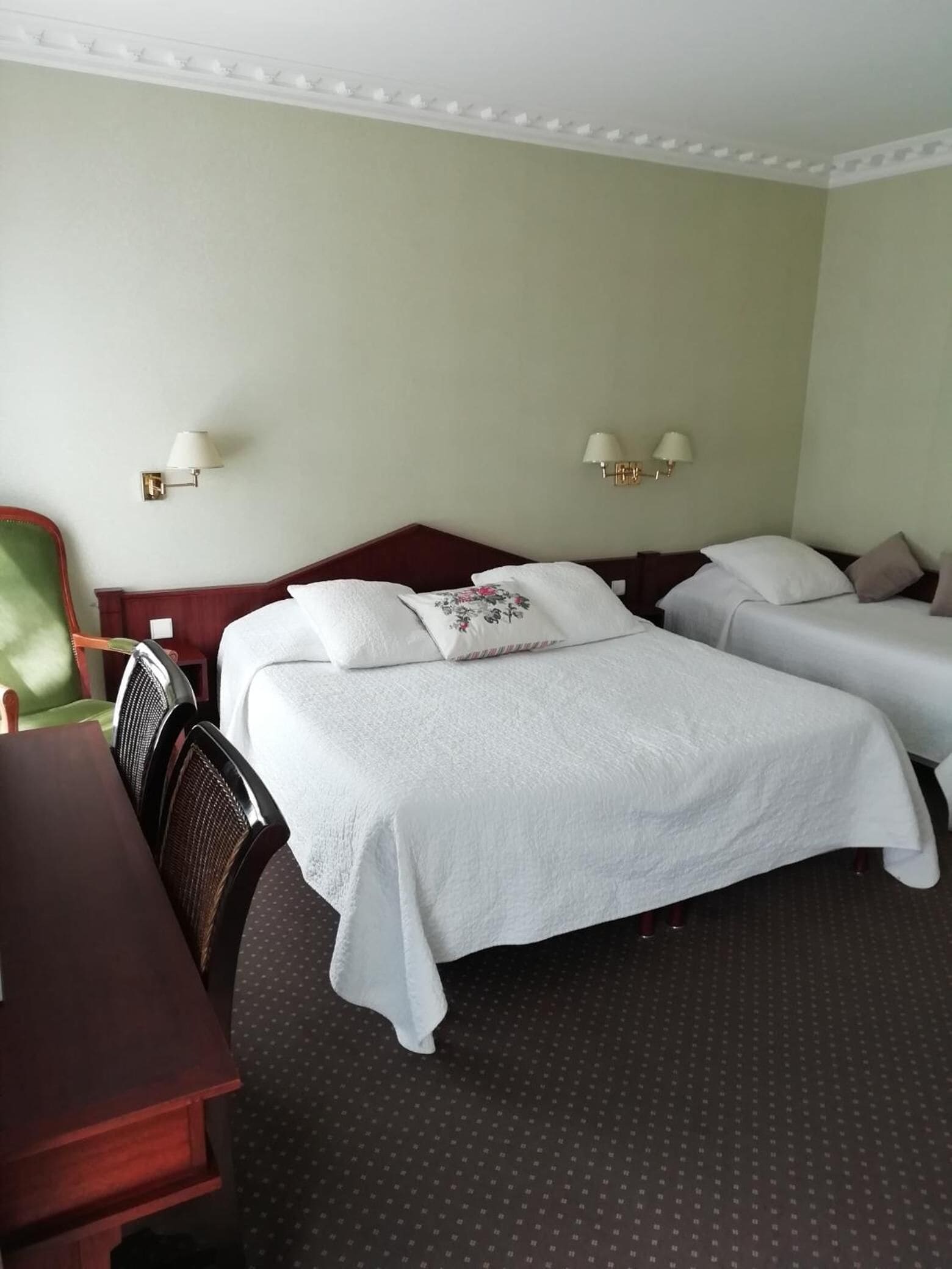 Ein Hotelzimmer mit zwei Betten, einem Schreibtisch und zwei Wandleuchten.