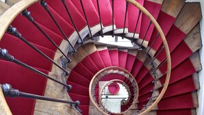 A spiral staircase with red carpeted steps and wooden handrails. - Hôtel du Manoir (Tours)