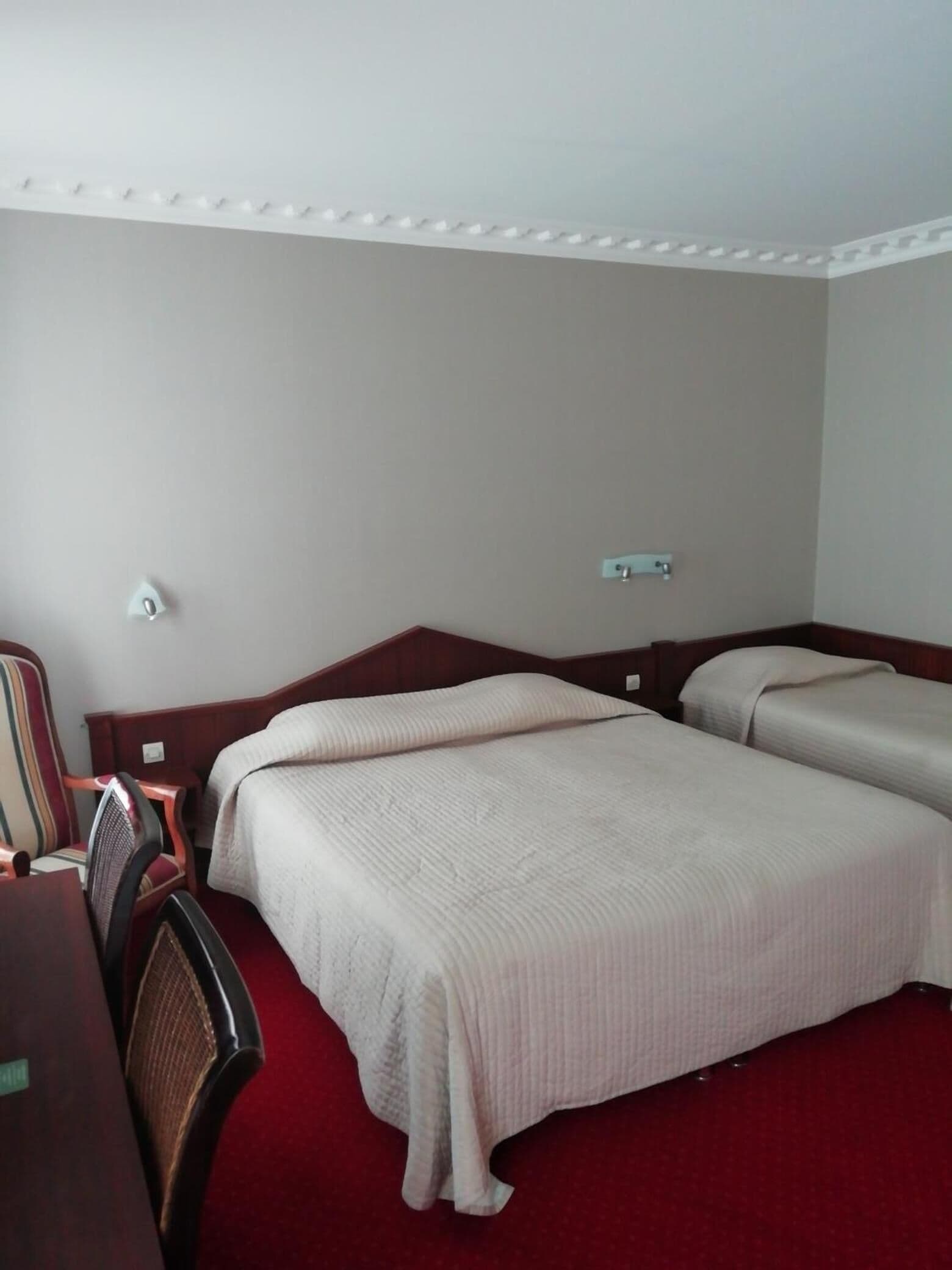 Una camera d'albergo con due letti, una scrivania e una sedia.