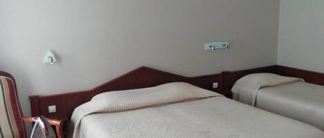 Una camera d'albergo con due letti, una scrivania e una sedia.