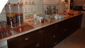 A breakfast buffet setup with various food and drink containers, glassware, and serving dishes. - Hôtel du Manoir (Tours)