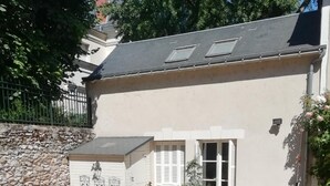 A building with a sloped roof, a garage with a decorative door, and a gravel driveway. - Hôtel du Manoir (Tours)
