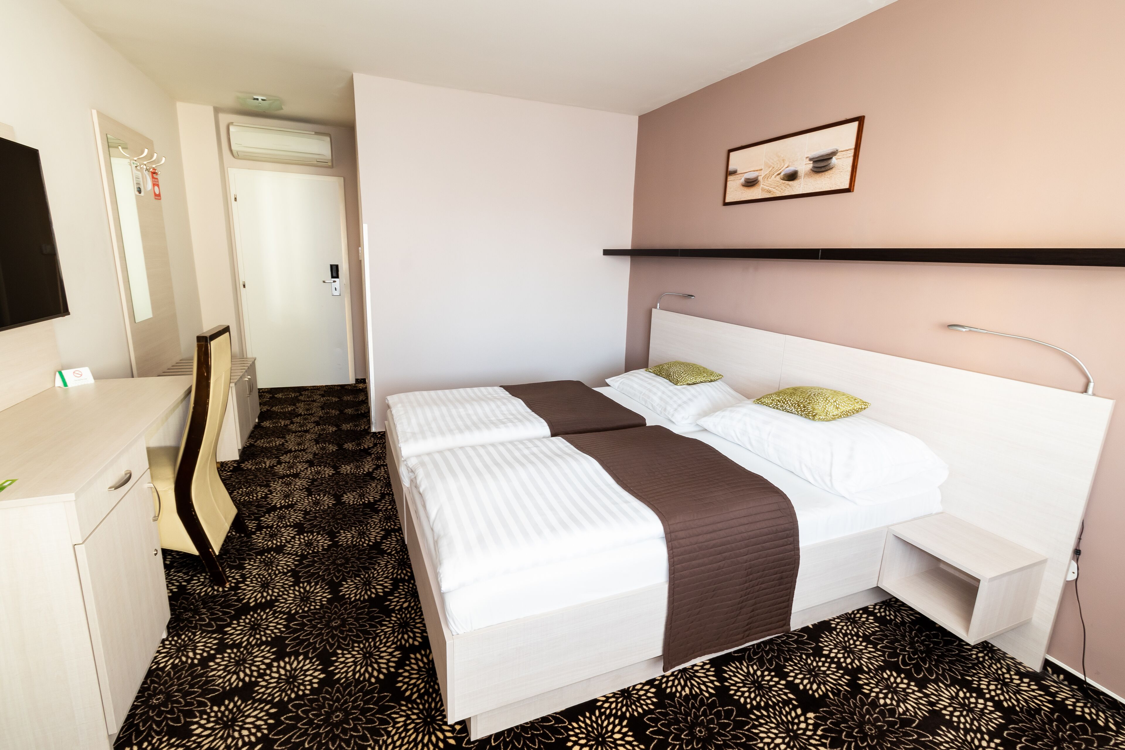 Una habitación de hotel con cama, mesita de noche y escritorio con silla.