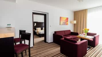 A hotel room with a striped carpet, a red sofa, a wooden table, and a bed with a headboard.