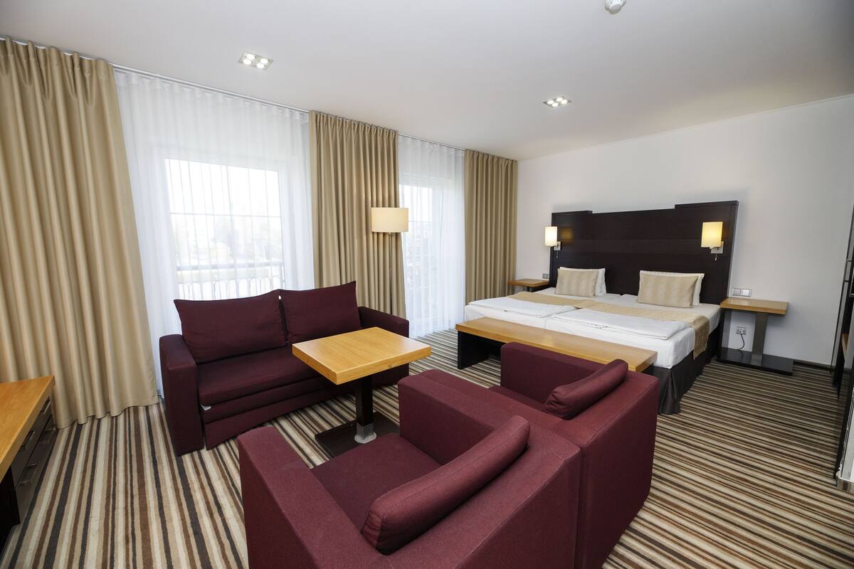 Une chambre d’hôtel avec un lit, un canapé, une petite table et une lampe.