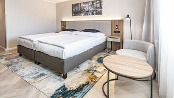 Quarto moderno com uma cama grande, mesas de cabeceira, uma cadeira e um tapete.