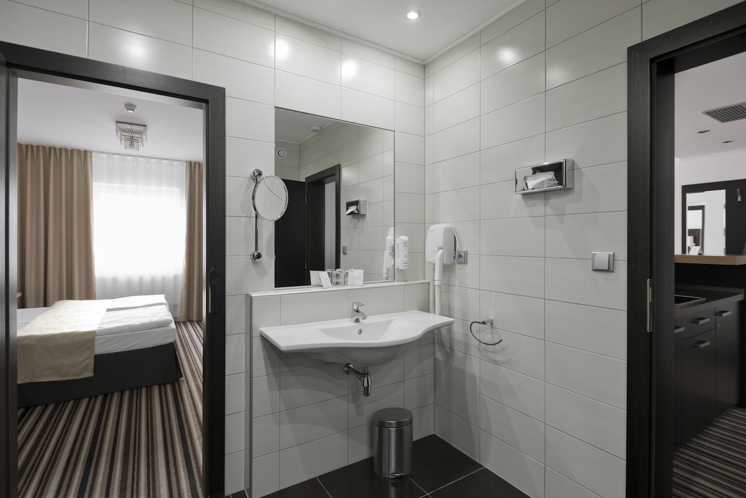 Een moderne hotelbadkamer met een grote spiegel, een wastafel en een toilet.