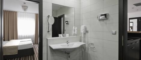 Un baño de hotel moderno con un espejo grande, un lavabo y un inodoro.