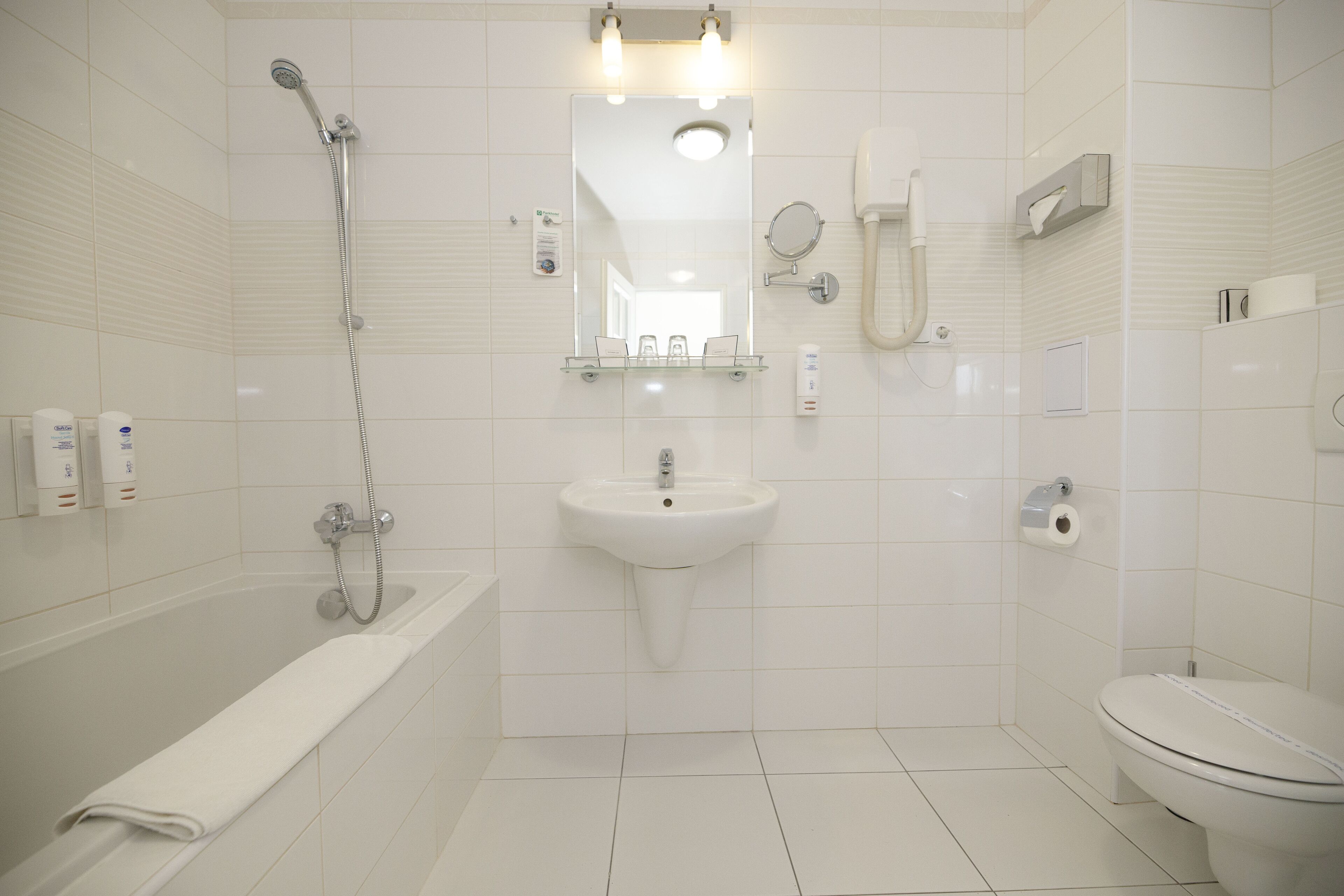 Een moderne badkamer met een badkuip, wastafel, toilet en een spiegel boven de wastafel.