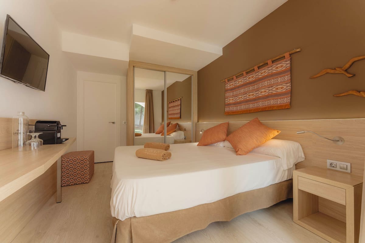 Une chambre d’hôtel moderne équipée d’un lit, d’une table de chevet et d’un téléviseur fixé au mur.