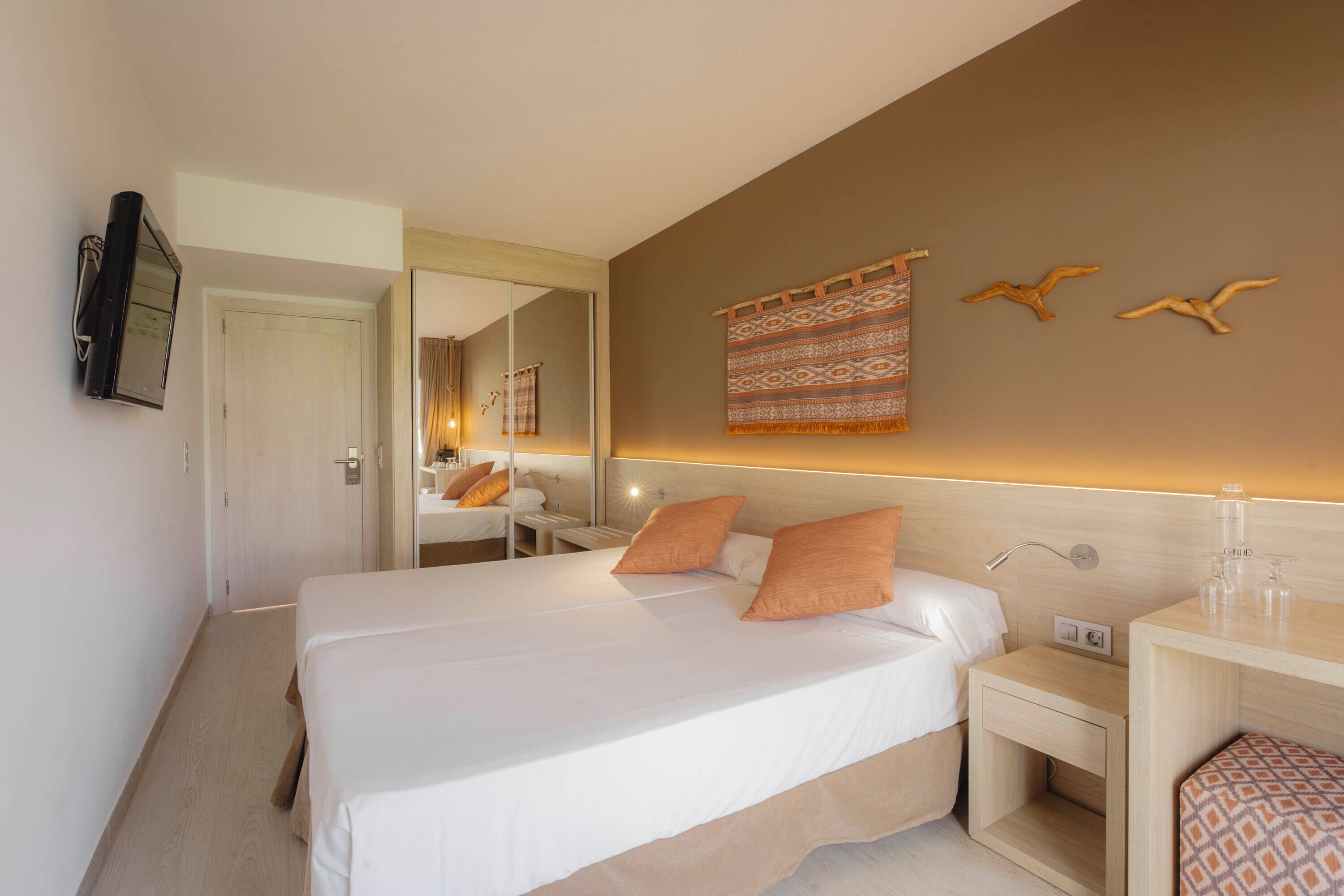Una camera d'hotel con un letto grande, comodini, uno specchio e una TV a muro.