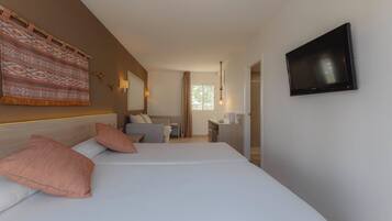 A hotel room with two beds, a TV, a desk, and a window.