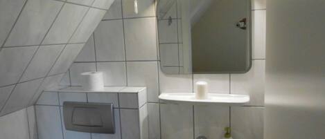 Un baño con un lavamanos blanco, un espejo encima y un perchero para toallas.