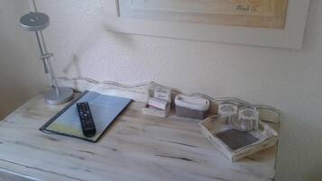 A white wooden table with a remote control, a notebook, and some containers.