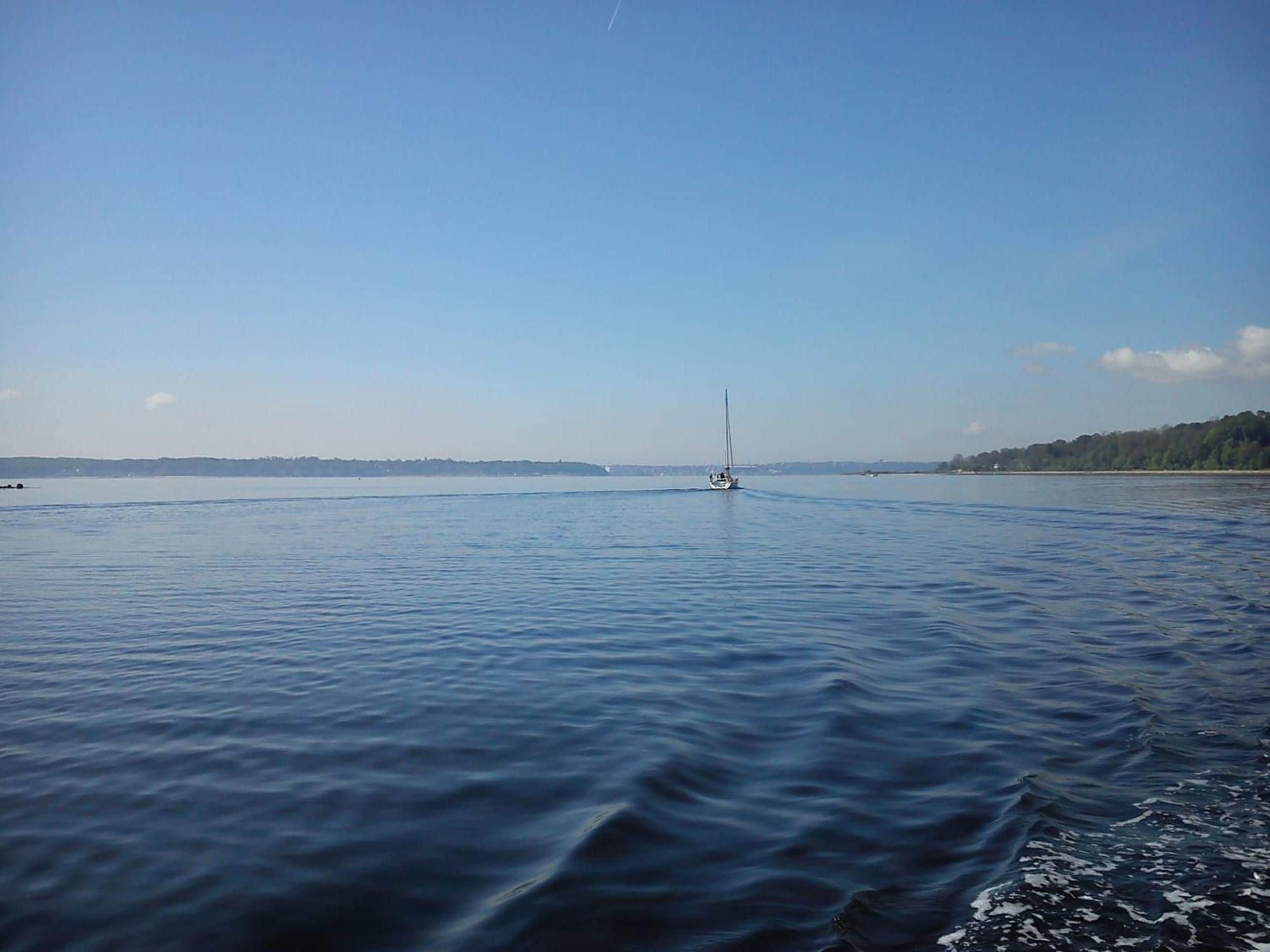 A calm body of water with a sailboat in the distance.
