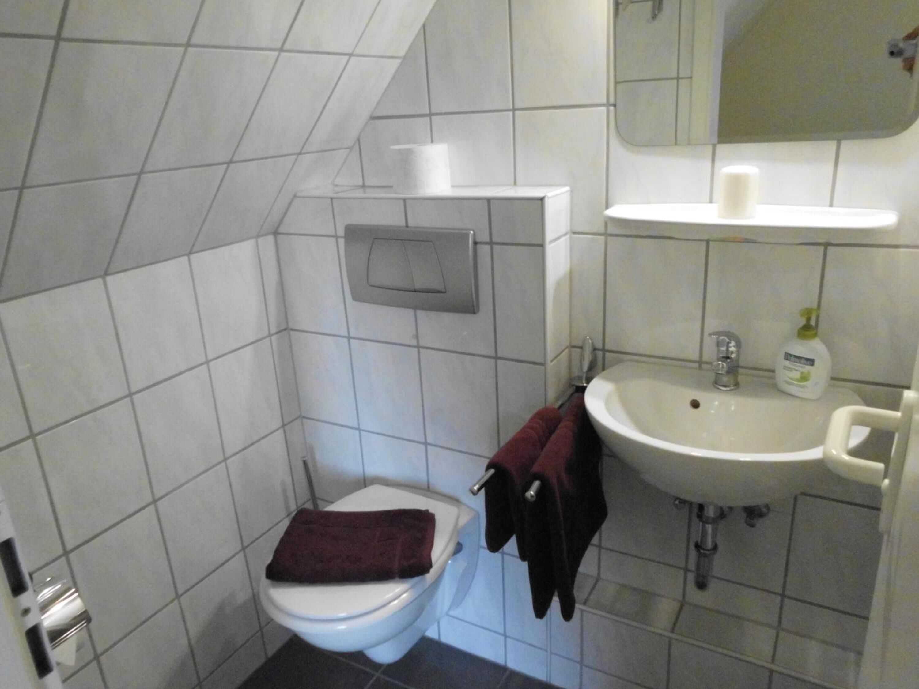 A small bathroom with a toilet, a sink, and a mirror.