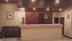 A reception desk with a wooden panel backdrop, a framed picture on the wall, and a door to the right. - Hotel Palanca (Porto)