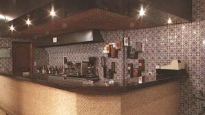 A kitchen with patterned tiles, a counter with various items, and a hood above the stove. - Hotel Palanca (Porto)