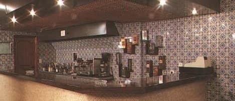 A kitchen with patterned tiles, a counter with various items, and a hood above the stove.