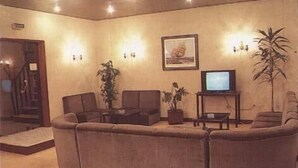 A living room with a sofa set, a television on a stand, a potted plant, and a framed picture on the wall. - Hotel Palanca (Porto)