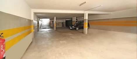A parking garage with concrete floors and yellow stripes on the walls.