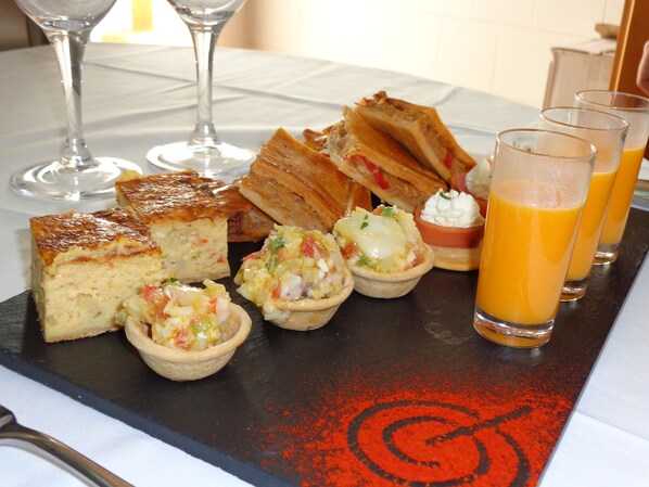 A breakfast tray with various pastries, a glass of orange juice, and a wine glass.