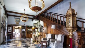 Un vestíbulo con piso a cuadros, una escalera y un reloj grande y ornamentado.
