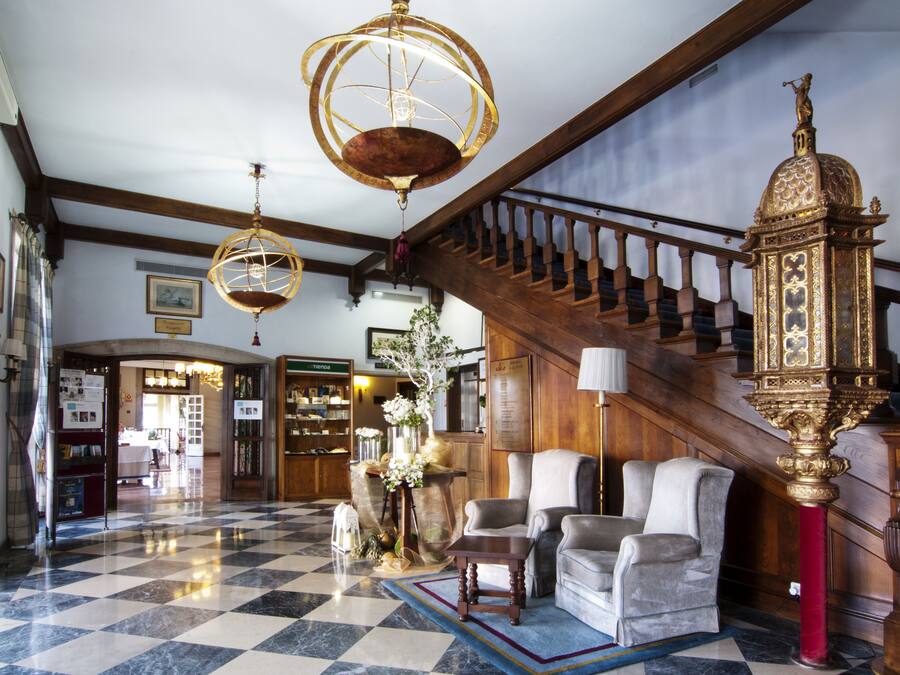 Un vestíbulo con piso a cuadros, una escalera y un reloj grande y ornamentado.