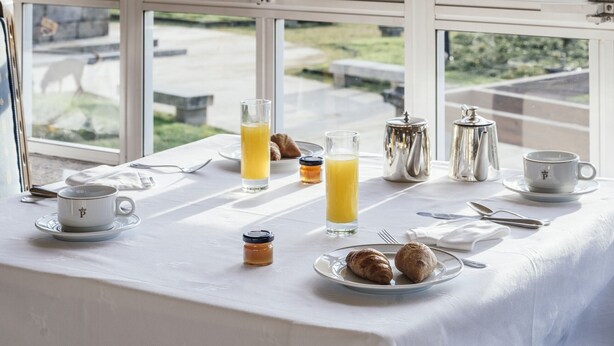 Una mesa de desayuno con vistas a un paisaje urbano a través de grandes ventanales.