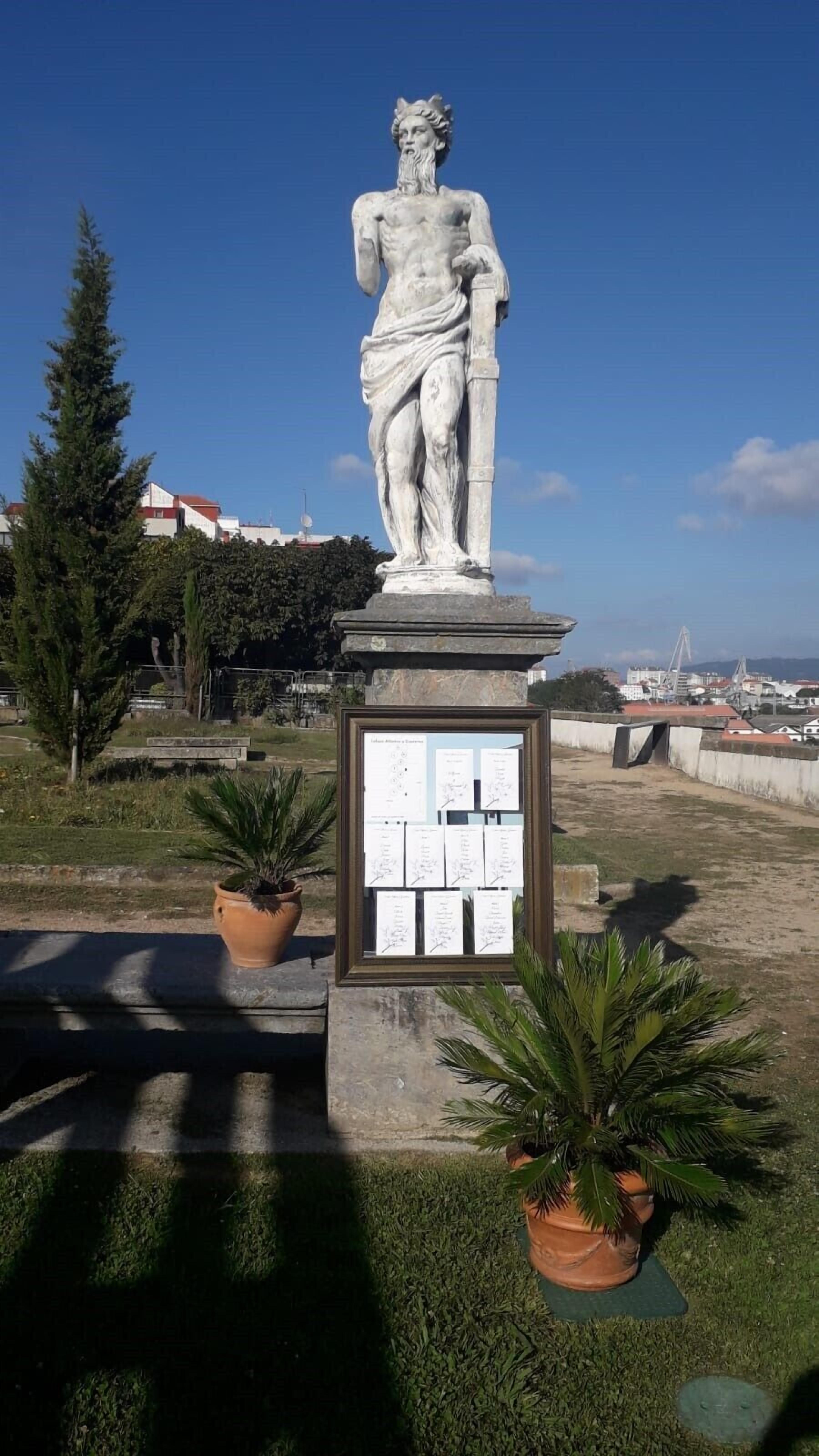 Una estatua de figura clásica sobre un pedestal con una placa de texto.